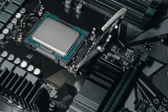 Angled close-up of a computer motherboard with an installed CPU in socket. Visible processor, socket latch, power components, and detailed circuitry. Modern PC hardware concept.