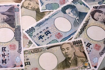 Japanese yen money bills pile on table. Japan banknotes of JPY currency close up. © Larysa