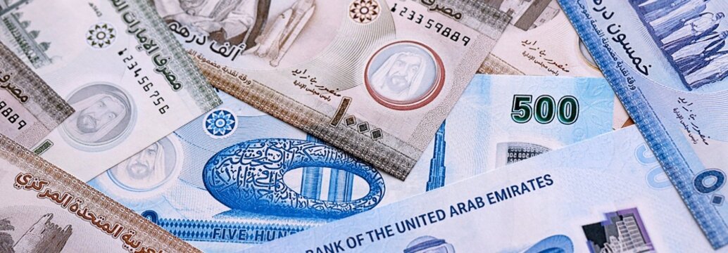 UAE dirham money bills pile on table. United Arab Emirates banknotes of AED currency close up.