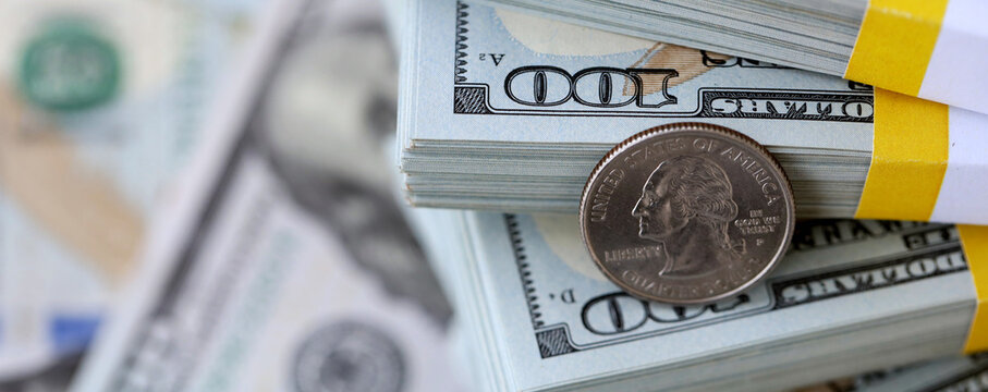 US coin lies among ten thousand dollars packs in stack on big amount of hundred dollar bills