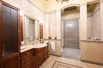 opulent classic bathroom with a wooden vanity, ornate mirror, tiled walls, mosaic floor,...