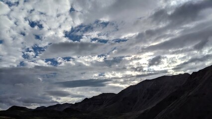 Mountain ridge silhouette beneath dramatic cloudy sky.