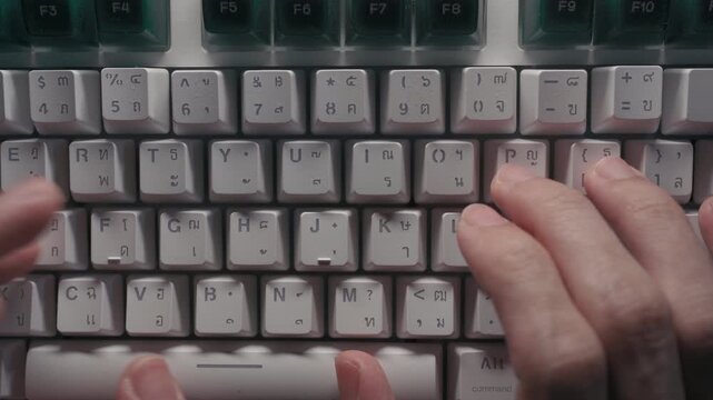 Close-up of Hands Typing on a Keyboard with Thai and English Characters