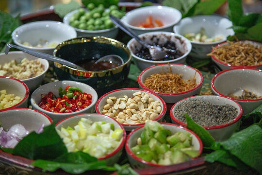 Traditional Thai appetizer Miang Kham set with various herbal ingredients like chili, lime, peanuts, and ginger served in small bowls on betel leaves for a healthy snack