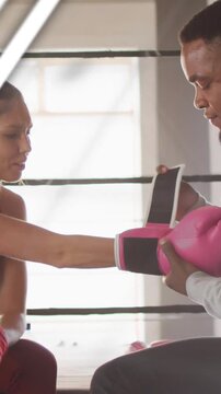 Vertical video: Boxer holding arm out, coach securing pink glove for boxing, teal data sweeping