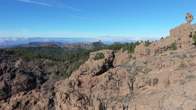 Stunning aerial footage revealing the iconic Roque Nublo and Teide volcano from behind the Ganifa arch on a sunny day in Gran Canaria