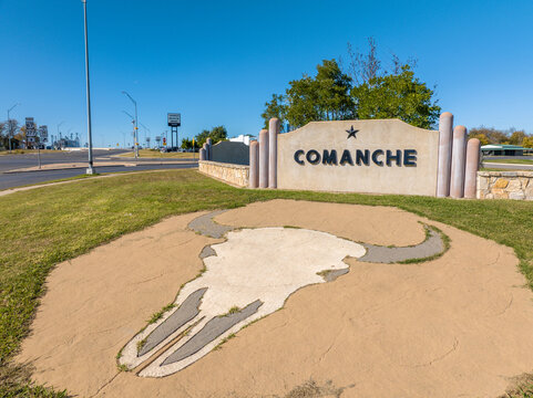 Stone Art Piece of Texas Longhorn Cow Skull in Front of Comanche Sign on Side of Highway in Comanche, Texas