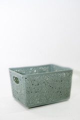 Sage green plastic basket with intricate floral lace pattern isolated on white