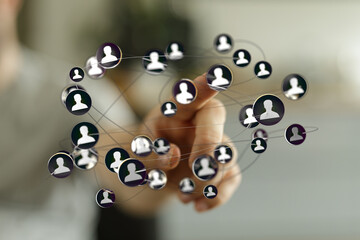 Close-up of a hand touching a network of people icons, representing social connections and digital communication in a t