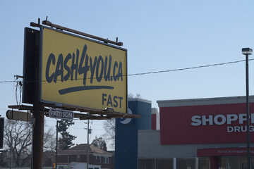 Naklejka premium traditional roadside billboard with cash4you advertisement and defocused Shoppers Drug Mart location at southwest corner of O'Connor Dr and Woodbine Av, Toronto