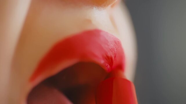 Woman with lip piercing applying red lipstick