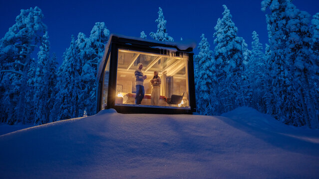 Cozy evening in a glass cabin surrounded by snow-covered forests in Akaslompolo, Lapland