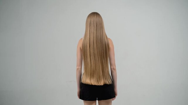 Blonde woman jumping with flowing hair in slow motion, back view