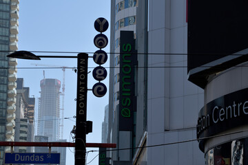 Naklejka premium shop signs and location markers in near silhouette outside CF Toronto Eaton Centre, a shopping mall, at Sankofa Square (looking south on Yonge St to SkyTower)