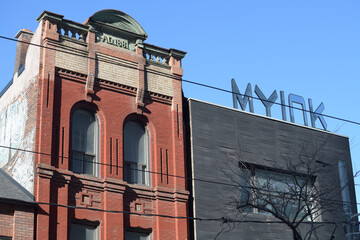 Naklejka premium historic late-Victorian commercial property at 242 Queen St W (originally, a bank) and the rooftop sign of MY Ink Tattoo Piercing & Nail Studio next door, Toronto