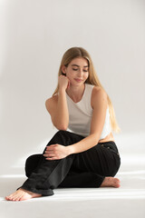Fototapeta premium Young blonde woman sitting on floor looking down minimalist lifestyle portrait