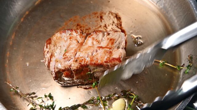 Beef steak cooking process with herbs and garlic in stainless steel pan