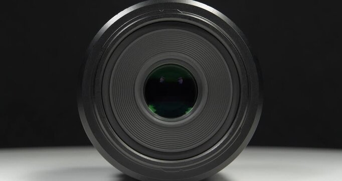 Black macro lens of Micro Four Thirds system, MFT or M4/3 or M43. Cinema 4K 60fps zoom-in video on a black background