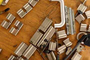 Close up of various locksmith tools, including lock cylinders, and other related parts, scattered...