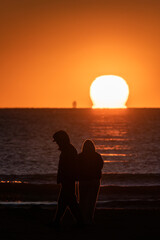Obraz premium Silhouette of Young Couple Watching Sunrise Over the Sea