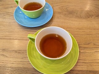 色鮮やかなカップ＆ソーサーに入ったハーブティーと木目調のテーブルの風景