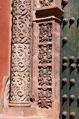A close-up view captures the elaborate stone carvings on a building entrance in Potosi. The ornate details highlight colonial influence. A studded door appears on the right.