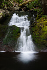 Obraz premium pyramidal flat cascade waterfall flowing water in two drops in mossy rocks in the forest