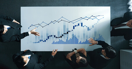 A business team engages in a discussion over financial graphs and market trends in a modern office...
