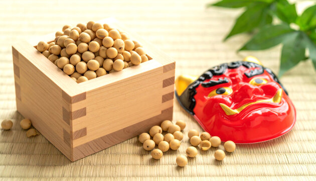 Traditional japanese setsubun celebration with roasted soybeans in a wooden masu box and a vibrant red oni demon mask on a tatami mat.