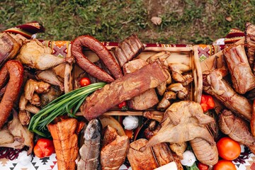 Assorted smoked meats and sausages on a rustic table with smoked fish and vegetables