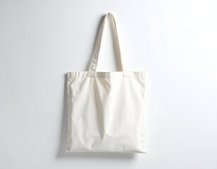 Plain, off-white canvas tote bag with two shoulder straps hangs