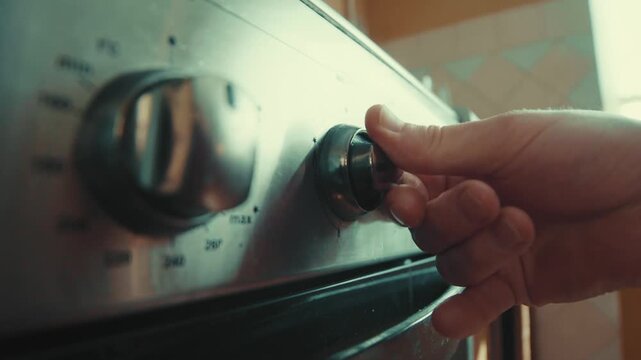 Close up of a man's hand turning on a gas stove burner  in a kitchen