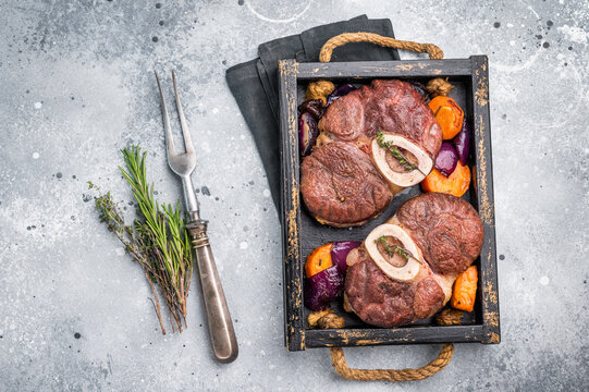 Flavorful ossobuco garnished with fresh herbs, osso buco shank ideal for impressing guests at your next dinner party. grey background. top view
