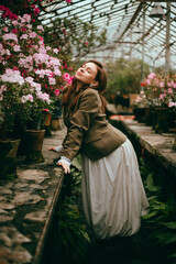Fototapeta premium Woman in a greenhouse explores azaleas among colorful flowers while enjoying the floral display and bright surroundings