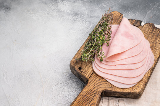 Delicious slices of cured ham on a wooden platter, ideal for entertaining and adding flavor to your dishes. white background. top view