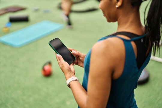 Portrait of a young black woman using a phone ant exting taking a break exercising in a gym, having a training workout in gym, healthy lifestyle and cardio exercise at fitness club concepts