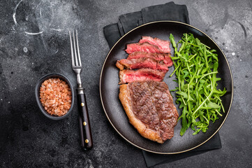 Fototapeta premium Appetizing grilled striploin steak with salad, inviting you to indulge in a mouthwatering culinary experience. black background. top view