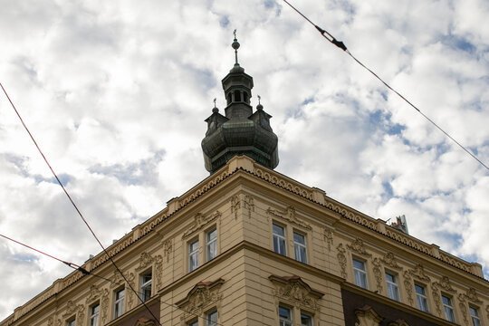 Baroque spire and ornate rooftop against cloudy sky, urban details with historic drama. Heavy cornices, sculpted pediments and rooftop finial create