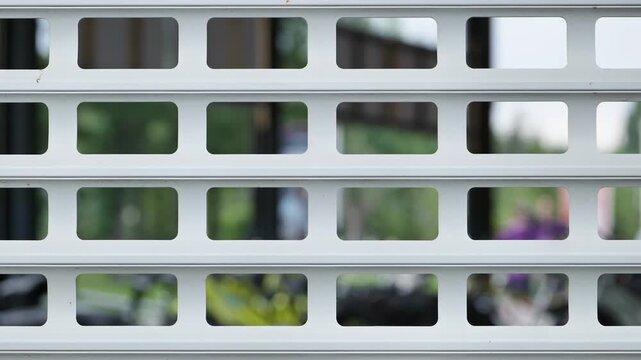 White metal security shutter grid with rectangular holes and blurred background