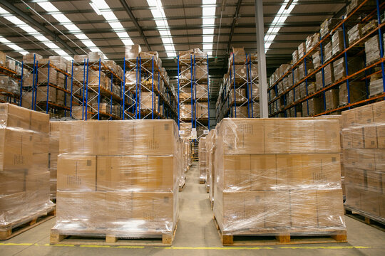 Interior of a warehouse distribution centre with high-bay racking systems and pallets of goods wrapped in plastic in the foreground, designed for efficient storage and logistics operations.