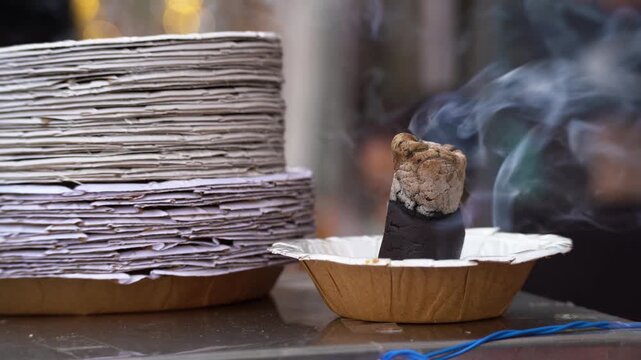 Smoking incense placed near stacked paper plates at an Indian street food stall, traditionally used to repel flies and mosquitoes while also reflecting cultural and religious practices.