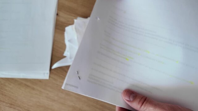 Hands tearing A4 paper sheets into four parts and stacking them for disposal. Concept of information security, paper shredding, and document destruction