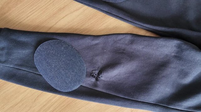 Repaired trousers with textile patches showing clothing fixing and reuse concept.