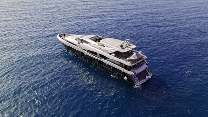 Aerial drone photo of luxury yacht with wooden deck anchored in Aegean island deep blue bay © aerial-drone