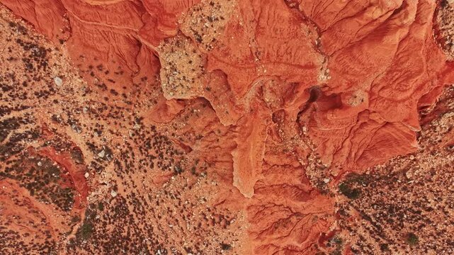 Bright red and orange rock formations show the unique patterns and textures found in the canyon. Sunlight highlights the details on the rocky surface, creating an interesting scene.