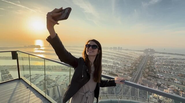 Woman taking selfie on Palm Jumeirah island at sunset, United Arab Emirates