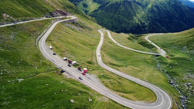 Dynamic aerial view of Transfagarasan mountain road winding through Fagaras Mountains, scenic serpentine highway in Romania