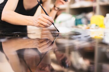 An artist skillfully brushes colors onto a reflective surface, bringing life to a creative project in a bustling studio. The atmosphere is filled with inspiration and focused energy