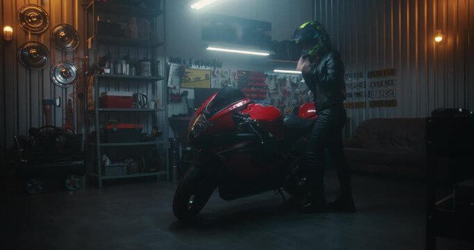 Stylish Asian Female in High Lace Up Boots and Leather Suit Enters Garage, Mounts Red Sport bike, Secures Helmet Visor, and Revs Engine For Departure. Concept Biker Subculture at Private Workshop.