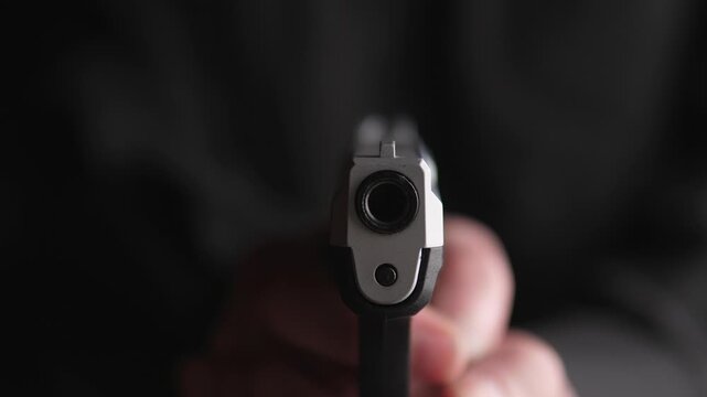 Gun Points At Camera. Dark Figure With Gun Visible. Crucial Image Showcasing Threatening Firearm Proximity. Intense Close Crosshair Scene With Shadowy Figure And Imminent Threat